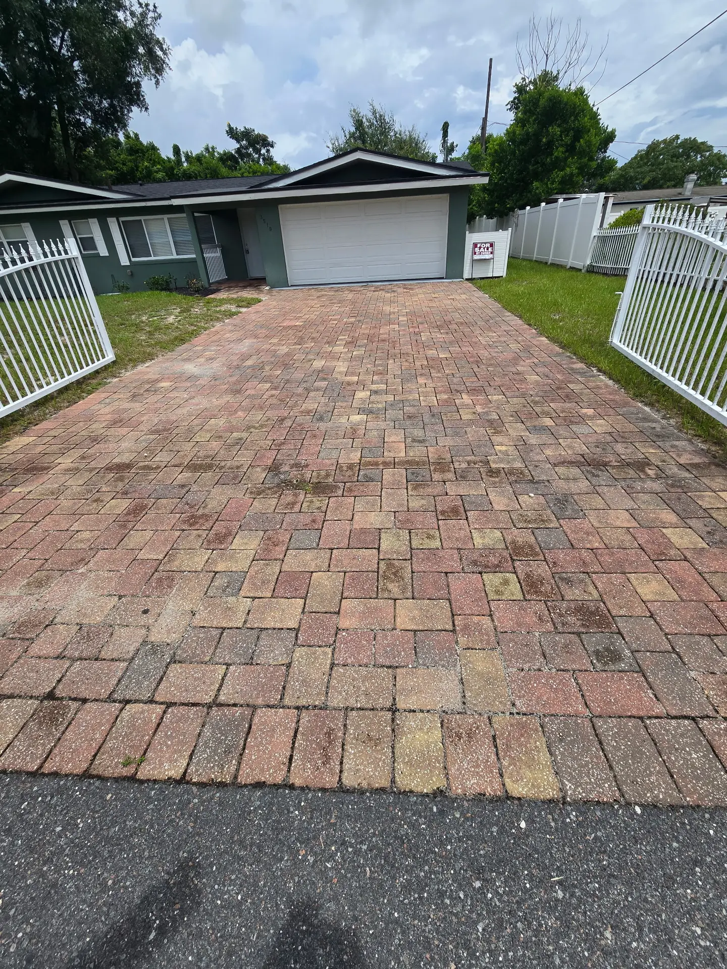 Paver driveway darkened by algae and traffic stains before paver cleaning in Mount Dora FL