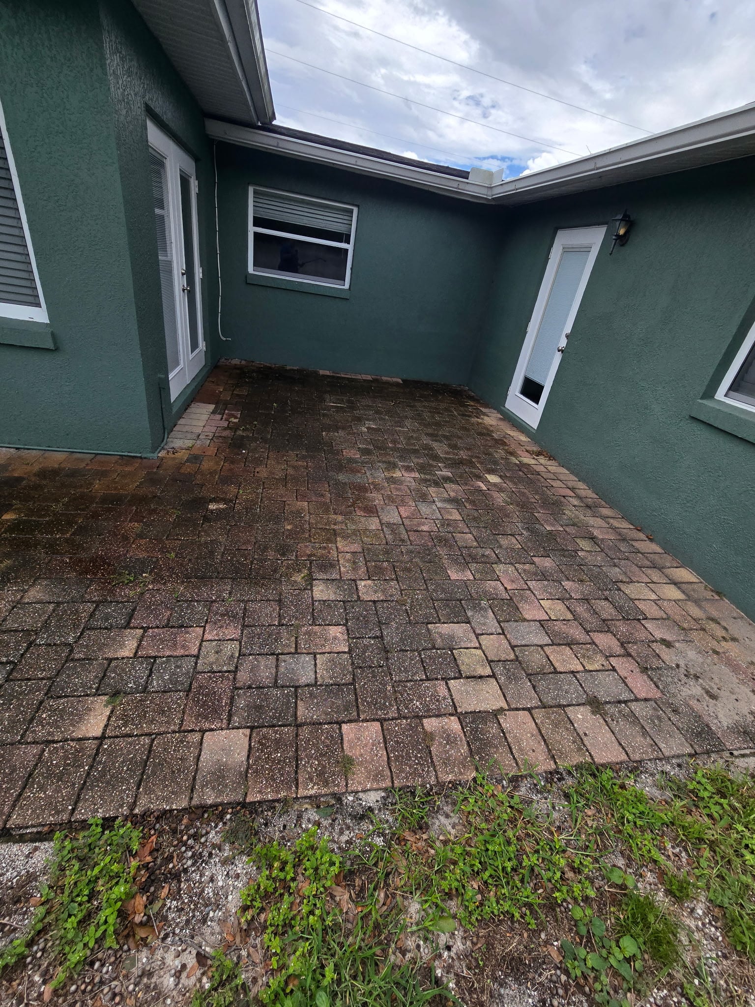 Shaded paver courtyard coated in green algae before paver cleaning in Mount Dora FL